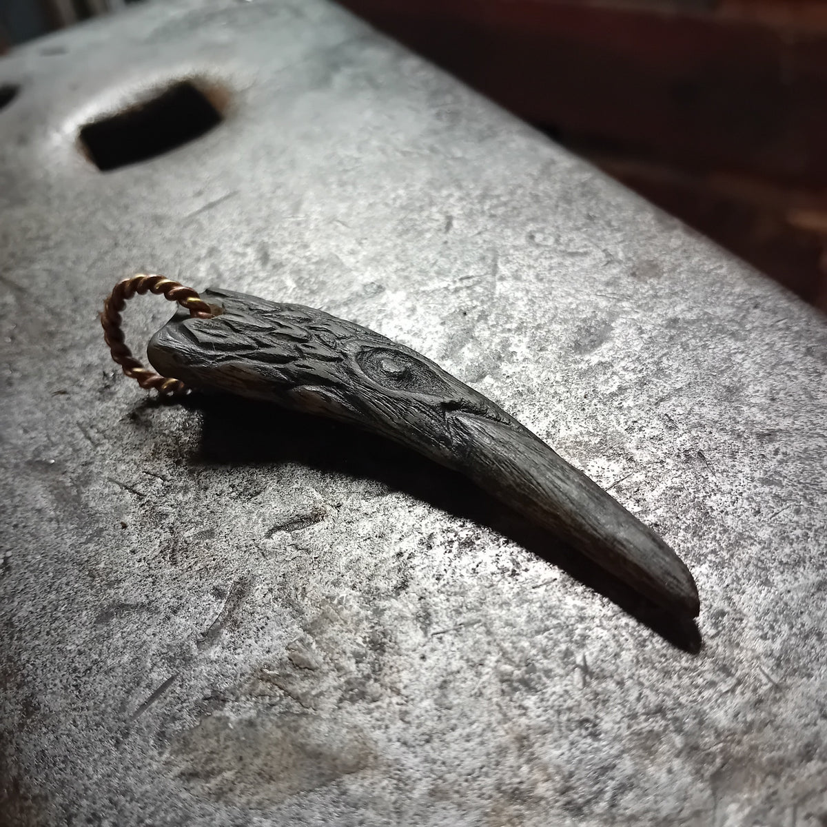 Raven head pendant showing carved feather detailing