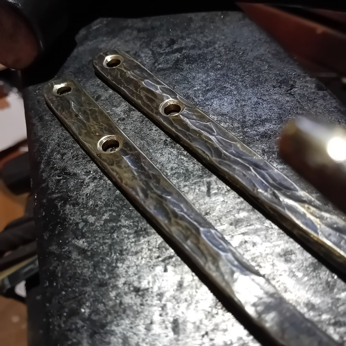 Close-up of hammer-textured brass hook mounting plates and fixing holes