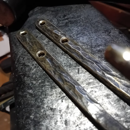 Close-up of hammer-textured brass hook mounting plates and fixing holes