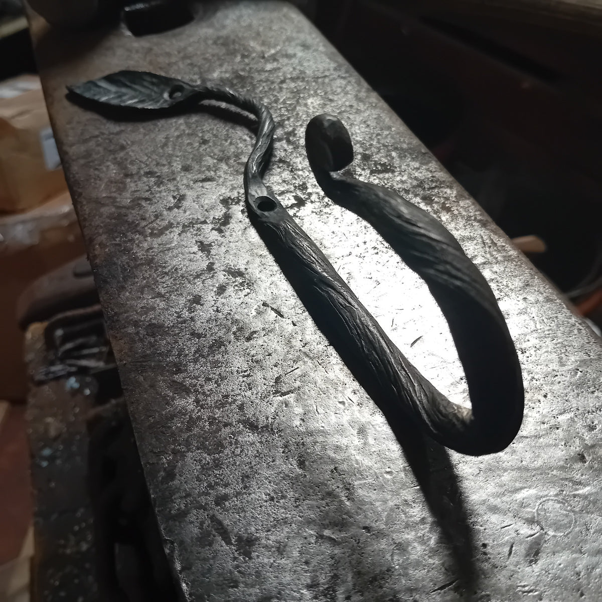 Side view of handmade iron leaf coat hook showing the curved scroll