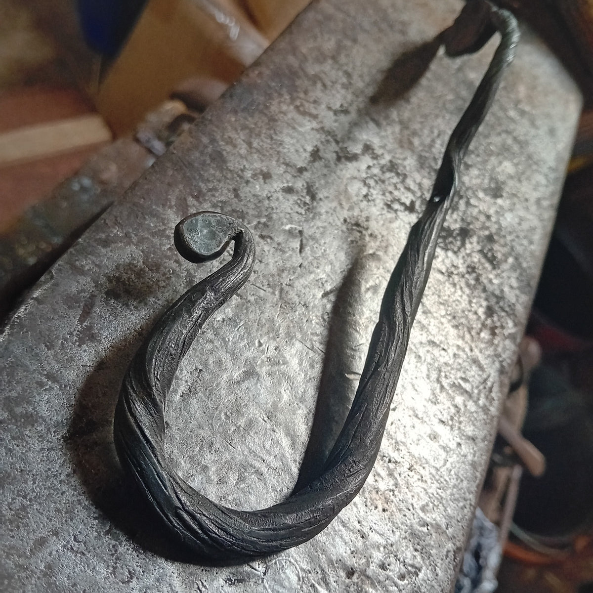 Close-up of curved and textured steel hook with decorative scroll tip