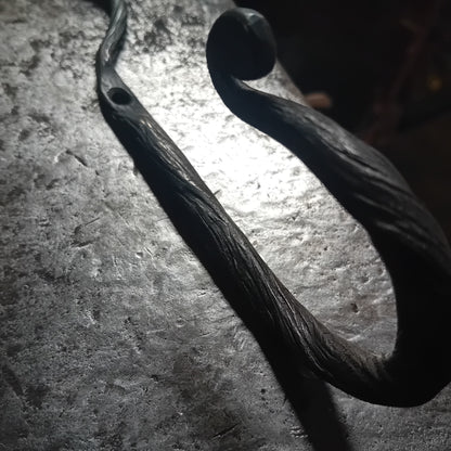 Detail of bark-textured hand-forged iron leaf wall hook and fixing hole