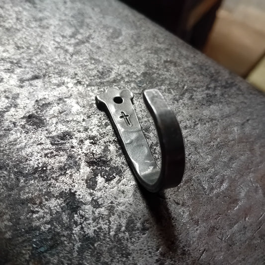 Single hand-forged steel cross wall hook on an anvil