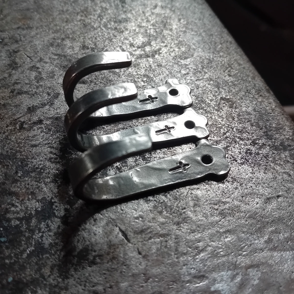 Three small hand-forged cross hooks showing curved profile