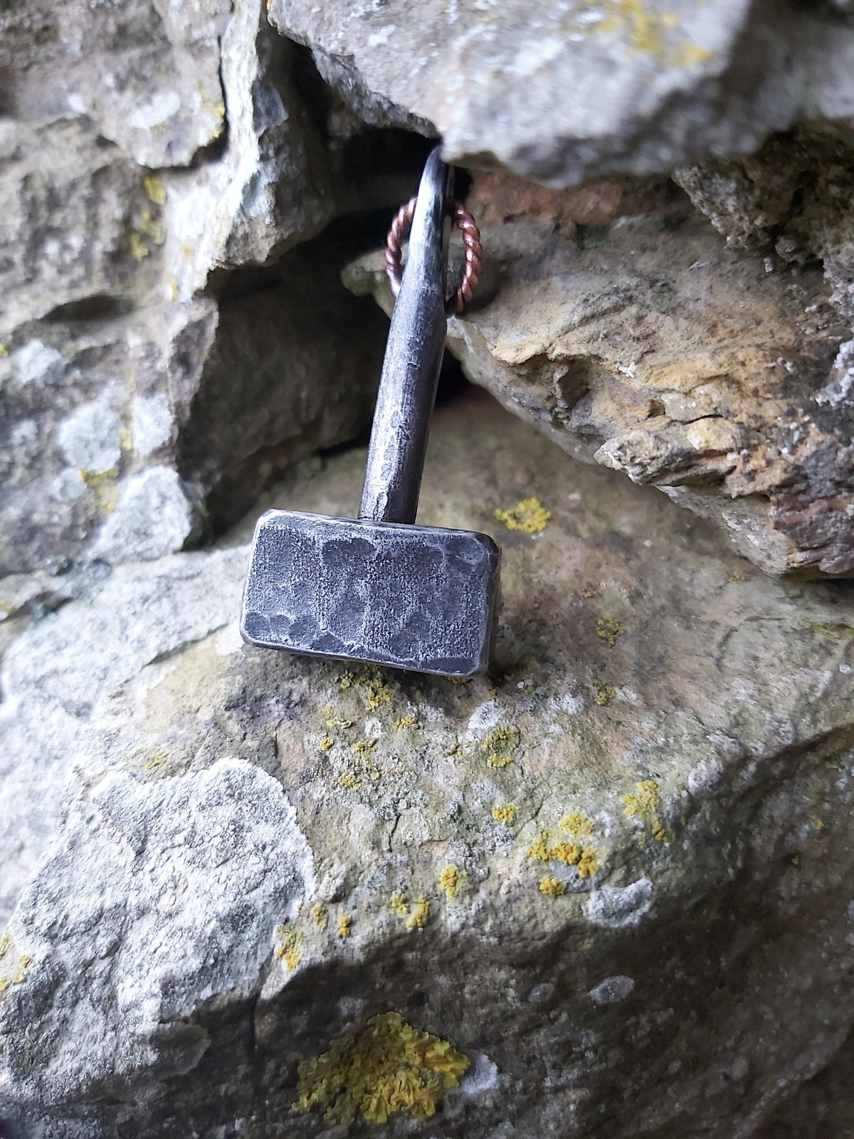 Hand-forged steel Thor's hammer pendant with twisted copper loop against Orkney stone