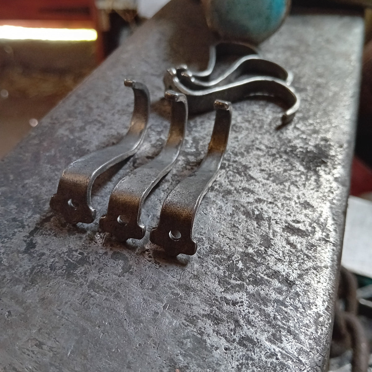 Hand-forged steel under-counter hooks showing fixing holes on the anvil