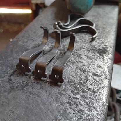 Hand-forged steel under-counter hooks showing fixing holes on the anvil