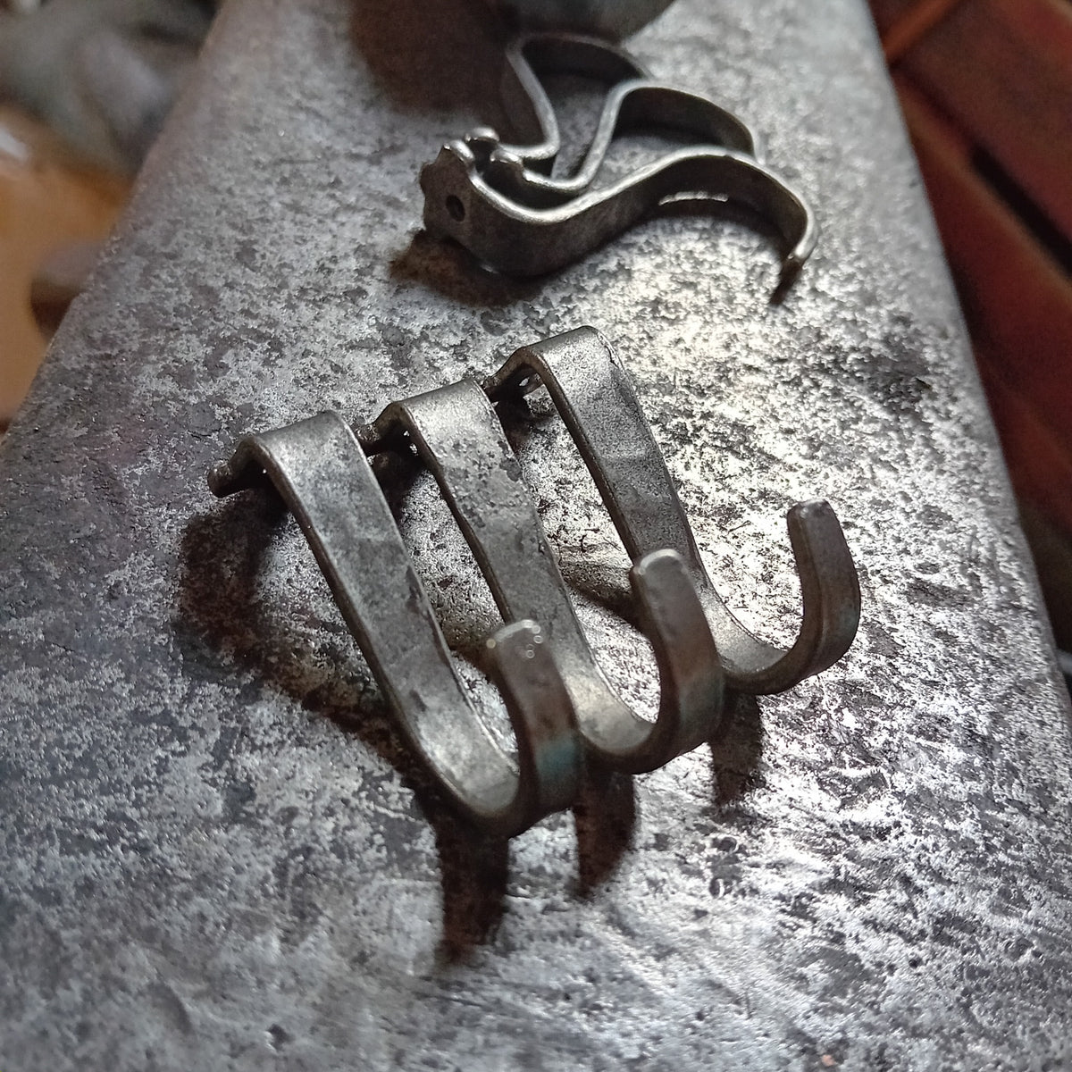 Close-up of curved under-counter hooks hand-forged in steel